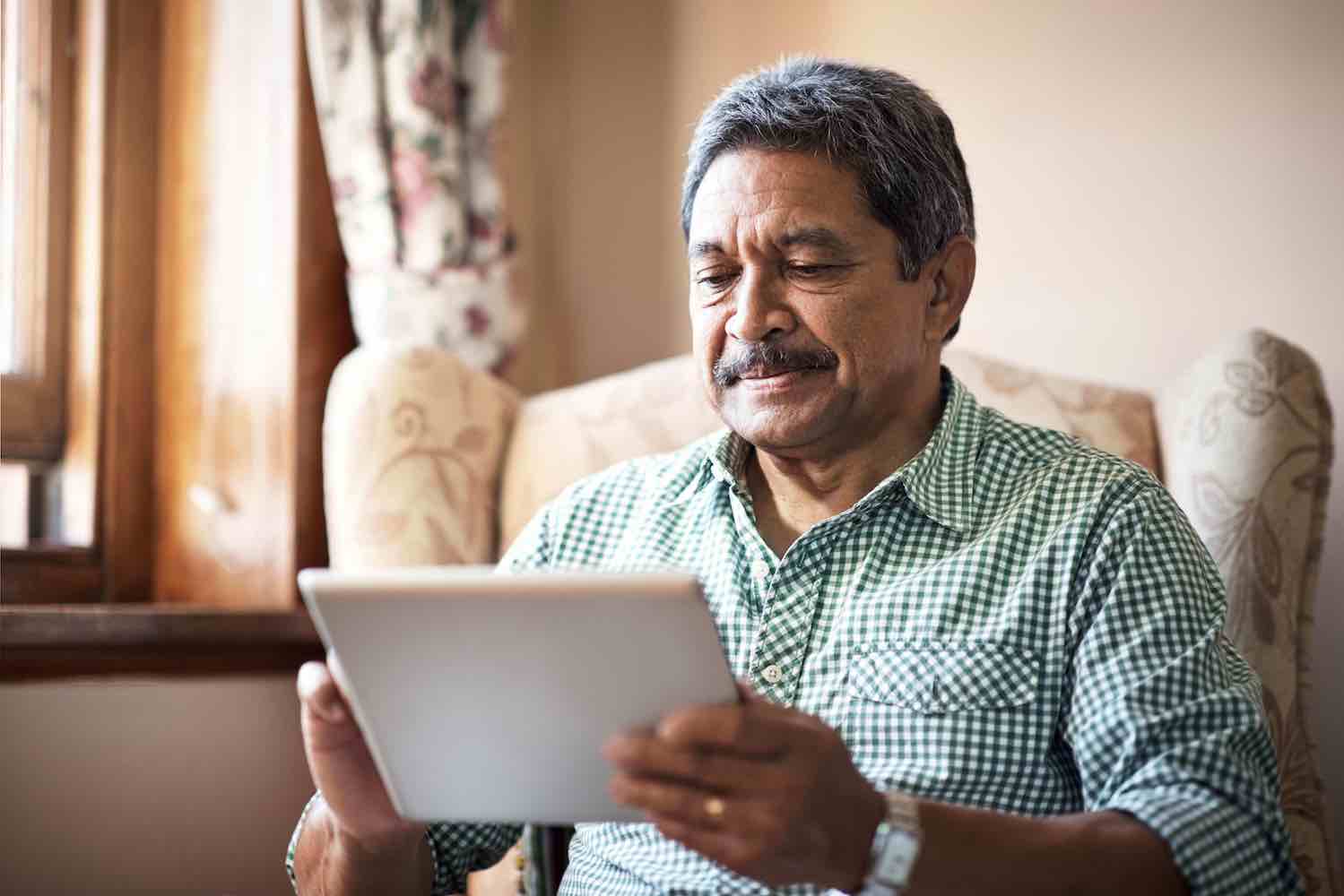 Shot of a senior man using his digital tablet while relaxing at home